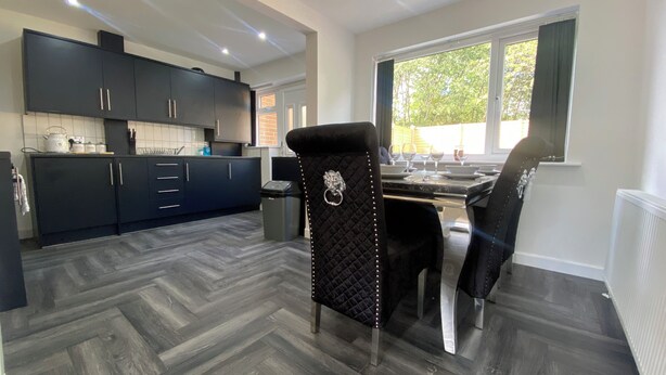 A modern kitchen with dark cabinetry and a herringbone-patterned floor.