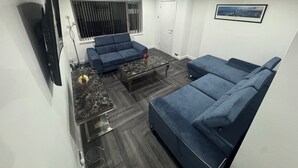 A modern living room with a blue sofa, a coffee table, and a TV mounted on the wall.
