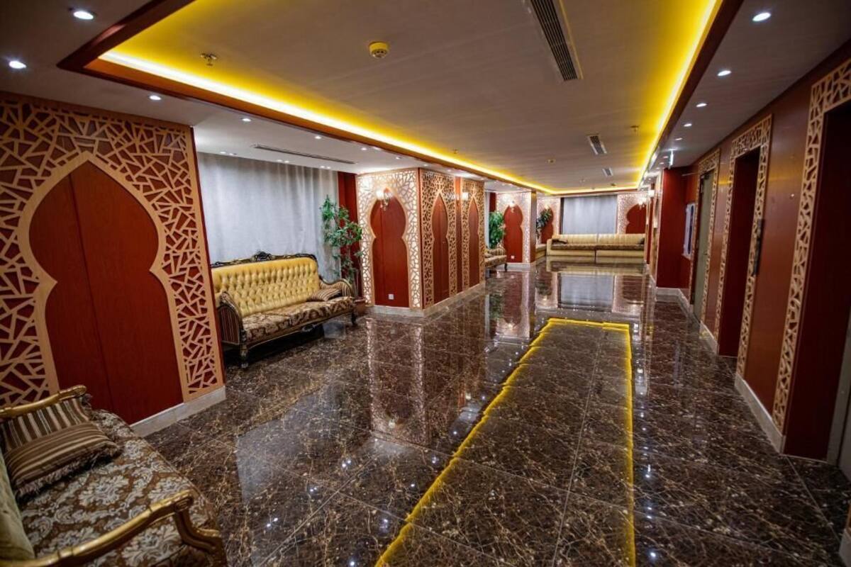 Vestíbulo de hotel con piso de mármol, decoraciones ornamentales en las paredes y zonas de estar.