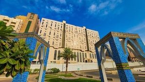 A large building with a central courtyard, surrounded by palm trees and a clear blue sky. - Misk Umm Al Qura Hotel (Makkah)