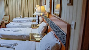 A hotel room with three beds, each with white linens and towels, a bedside lamp, and a mirror. - Misk Umm Al Qura Hotel (Makkah)