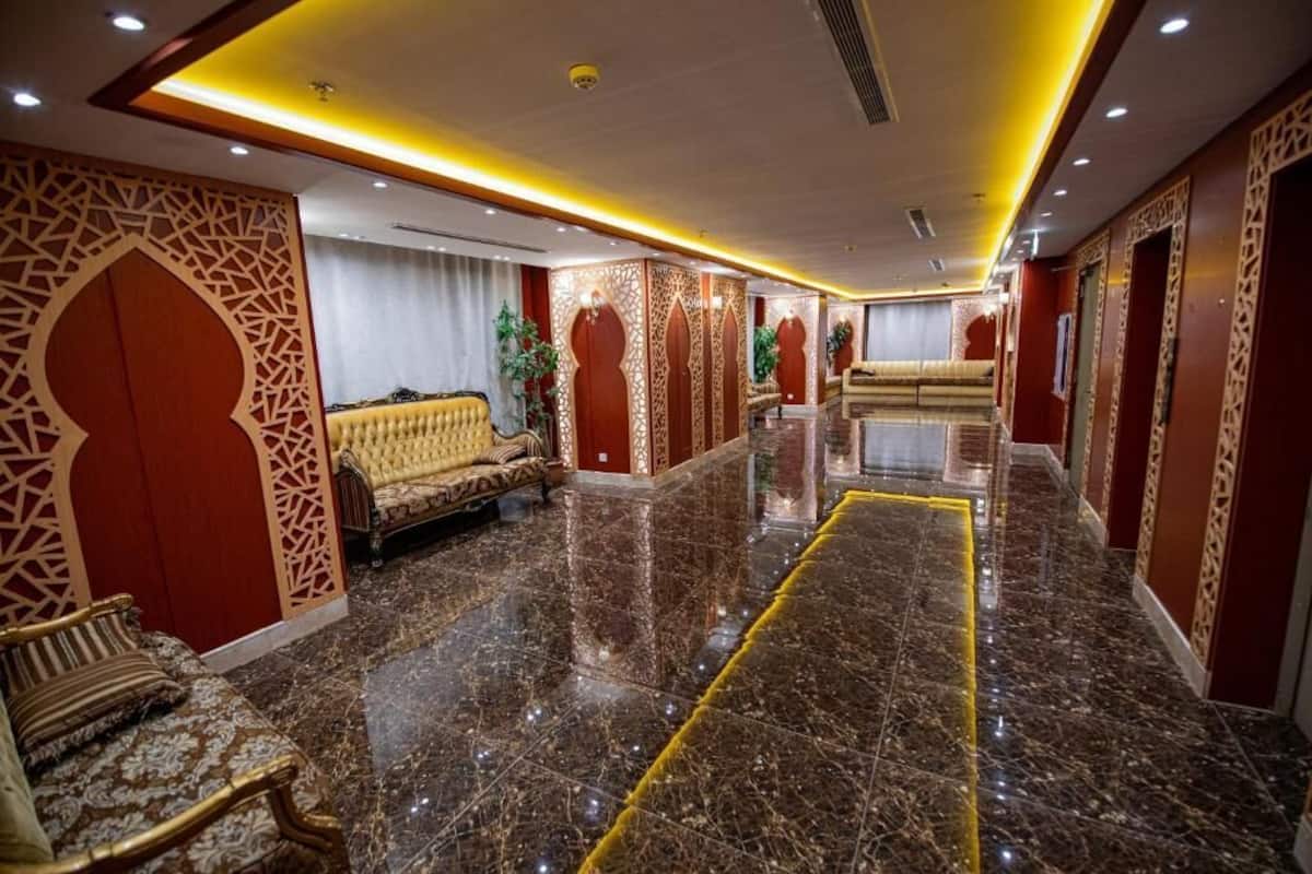 Vestíbulo de hotel con piso de mármol, decoraciones ornamentales en las paredes y zonas de estar.