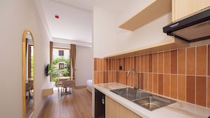 Una cocina moderna con lavavajillas incorporado, un lavamanos de acero inoxidable y una campana extractora negra.