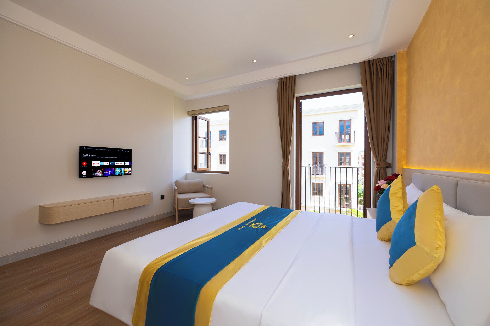 Une chambre d’hôtel avec un grand lit, un téléviseur fixé au mur, une petite table et une chaise.
