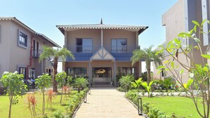 A two-story building with a balcony, a sign reading "LION", and a paved walkway leading to the entrance. - Gold Lion Resort (Talala)