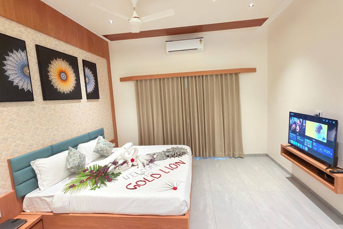 A hotel room with a bed, a television, and artwork on the wall.