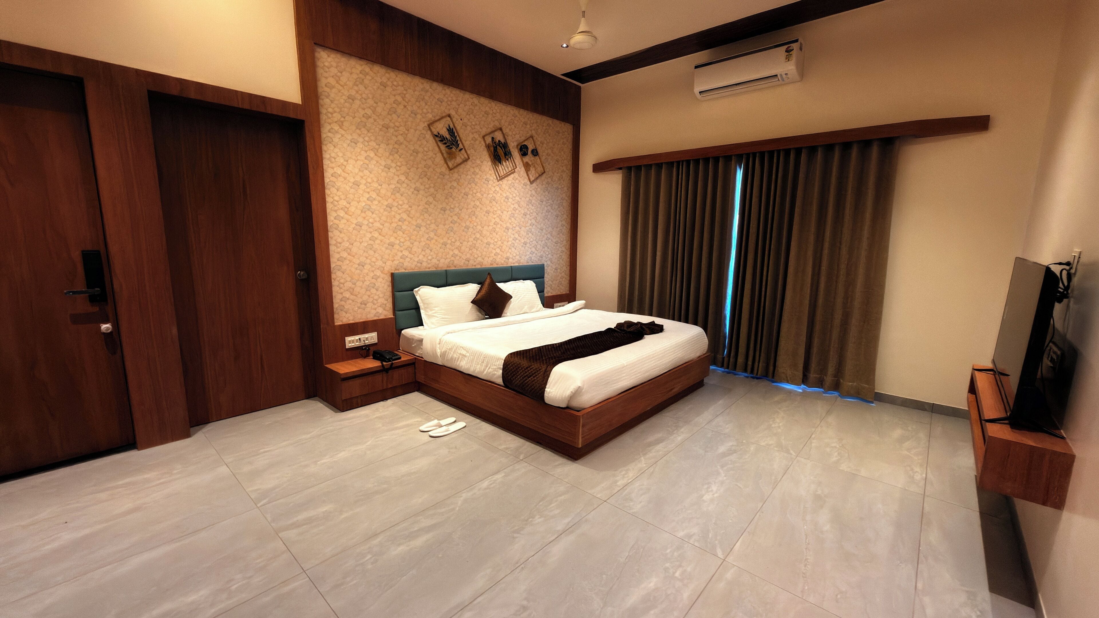 Habitación de hotel moderna con una cama grande, piso de madera, televisión de pantalla plana y aire acondicionado integrado.