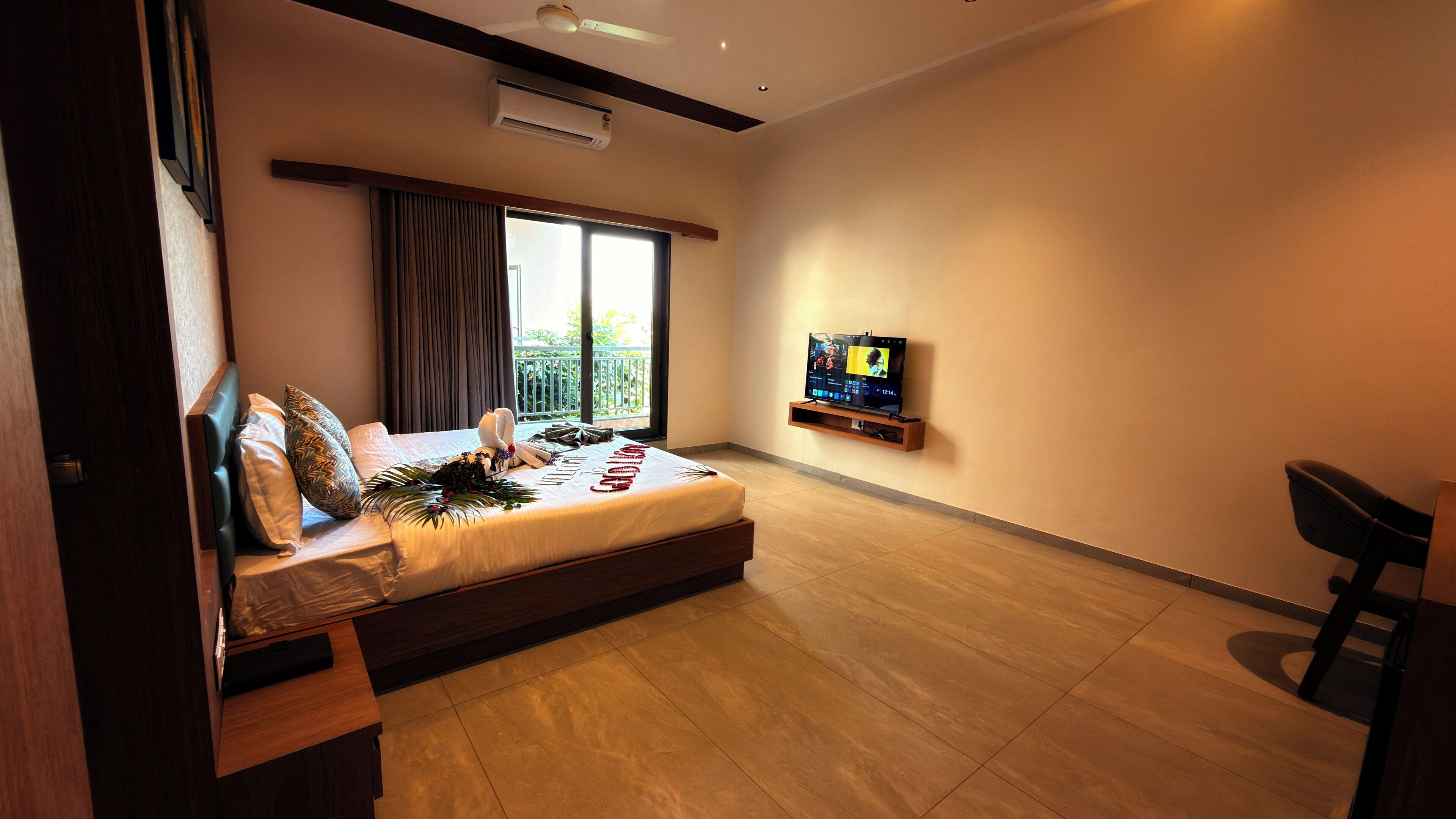 A modern hotel room with a bed, a TV, and a balcony.