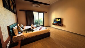 A modern hotel room with a large bed, a TV on a wooden shelf, and a balcony with curtains. - Gold Lion Resort (Talala)