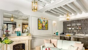 Un salon avec une cheminée, un canapé, une table basse et un coin cuisine avec un mur recouvert de carreaux.