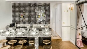 Une cuisine moderne dotée d’un plan de travail en marbre, d’un crédence à motifs noir et blanc et d’éléments décoratifs dorés.