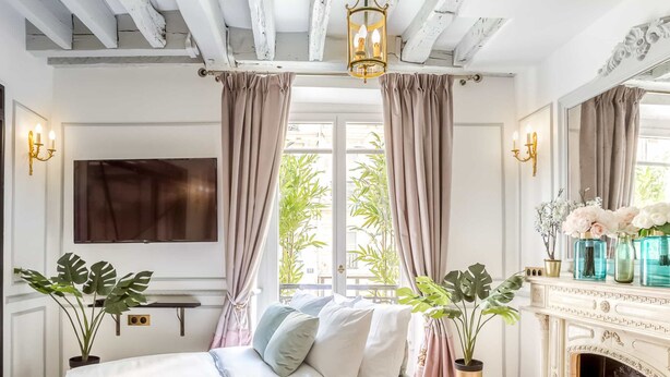 Une chambre à coucher avec un lit, une cheminée et une grande fenêtre avec des rideaux.