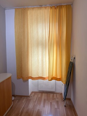 A room with a wooden floor, a white wall, and a yellow curtain.