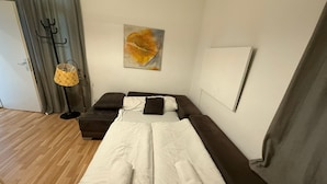 Um quarto com uma cama, um sofá, um cabideiro e um quadro na parede.