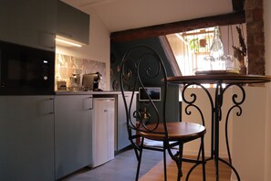 A kitchen with a dining table and chairs, a coffee machine, and a window with a view of the outdoors.