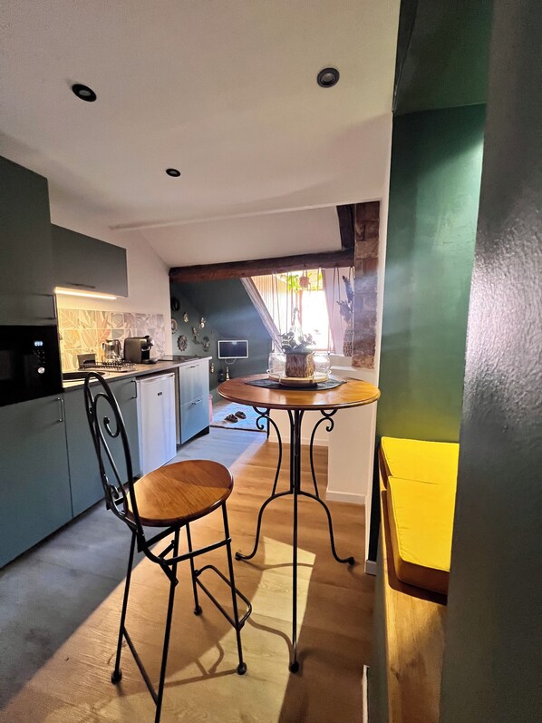 A compact kitchen with a dining area, a small table, and a chair.