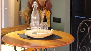 A dining area with a round table, a chair, a mirror, and decorative plants.