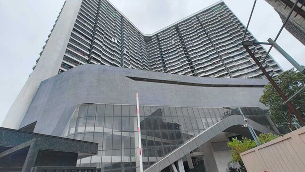 A modern building with a curved glass facade and a prominent staircase leading to the entrance. - Treebo Premium Shahad (Kalyan)
