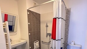 Et badeværelse med bruser, toilet og håndvask.