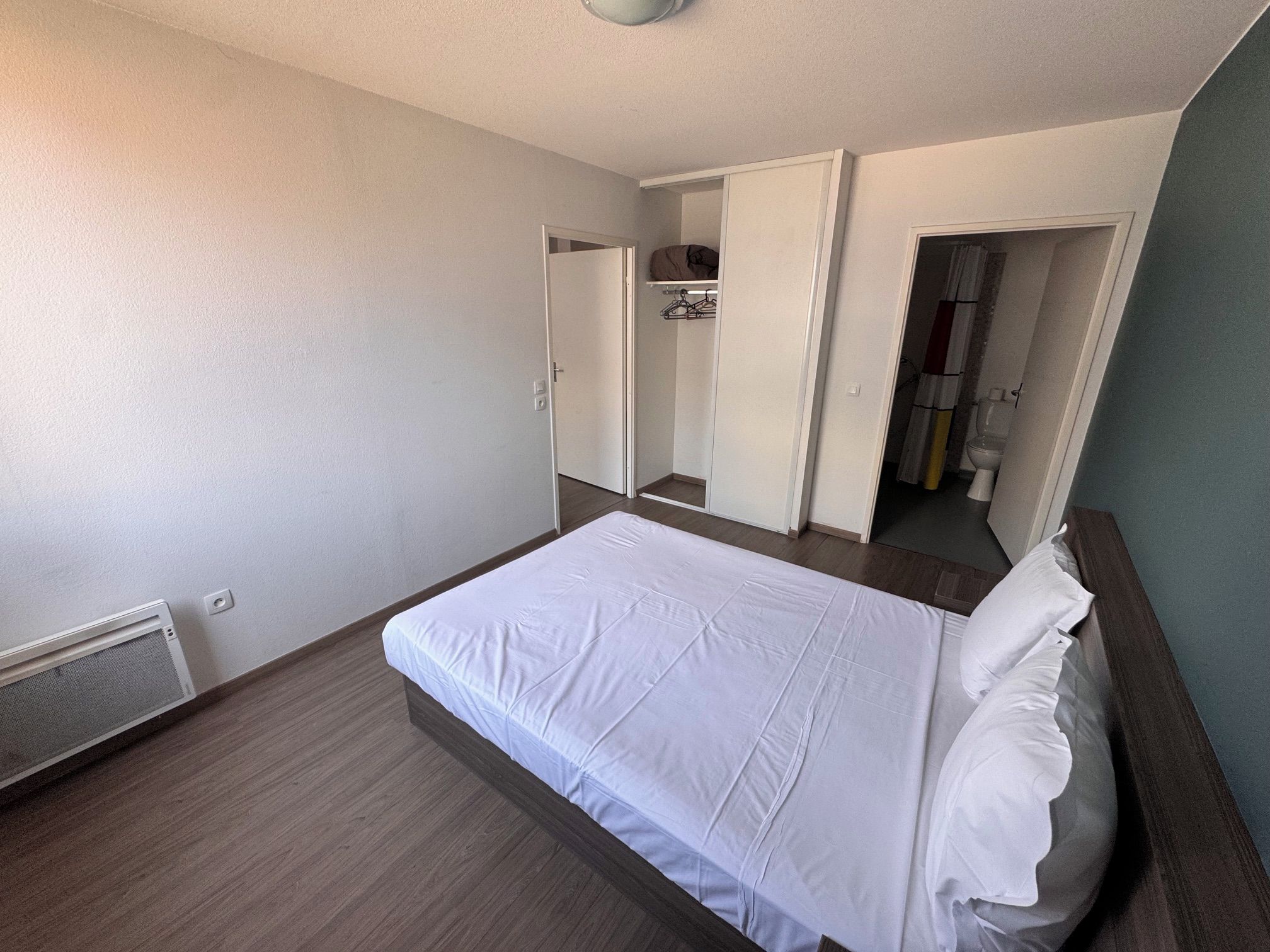 Une chambre à coucher avec un lit, une armoire et une salle de bain.