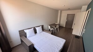 Et hotelværelse med en seng, et skrivebord, en stol og et klædeskab.