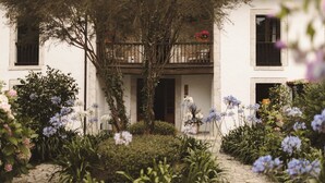 A white building with a balcony, surrounded by a garden with various plants and flowers. - Luxurious villa Floravista for 12 people in Piloña (Valle, Piloña)
