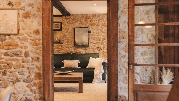 A rustic room with stone walls, a wooden ceiling, a green sofa, a wooden coffee table, and a patterned rug. - Luxurious villa Floravista for 12 people in Piloña (Valle, Piloña)