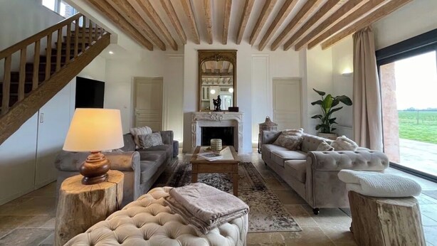 Un salon spacieux doté d’une cheminée, d’un escalier et d’une grande fenêtre donnant sur l’extérieur.