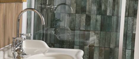 Un baño con un lavamanos pedestal blanco, una ducha con puerta de cristal y pared de azulejos.