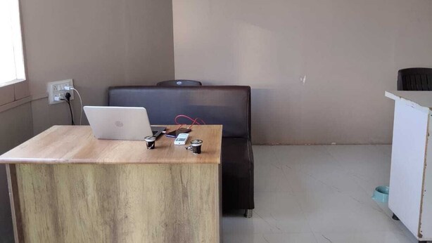 A small office space with a wooden desk, a laptop, a chair, and a white cabinet.