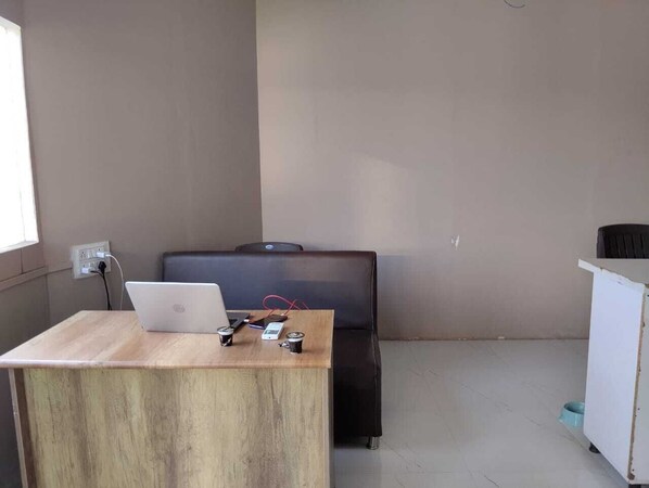A small office space with a wooden desk, a laptop, a chair, and a white cabinet.
