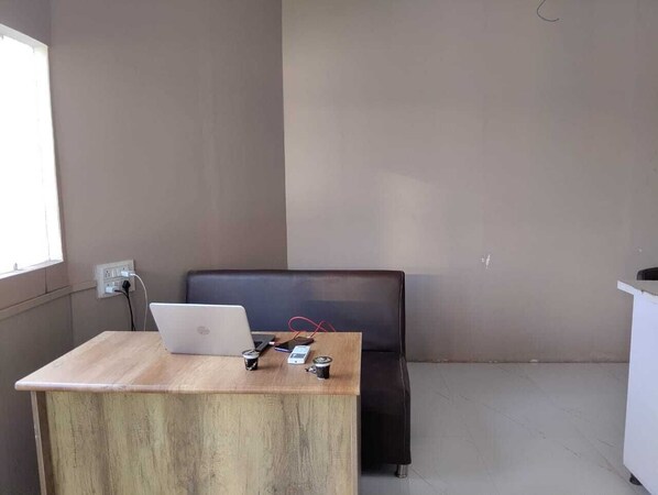 A room with a wooden desk, a laptop, and electronic devices.