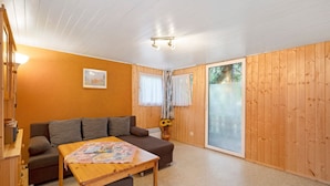 Una habitación acogedora con un sofá, una mesa, una lámpara y un ventanal con cortinas.