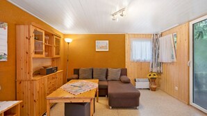 Una habitación acogedora con un sofá, una mesa con un mapa, un armario y un radiador.