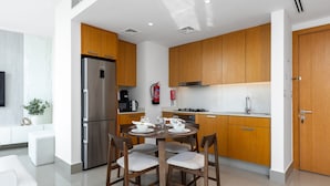 Une cuisine moderne avec des meubles en bois, un réfrigérateur en acier inoxydable et un coin repas équipé de quatre chaises.