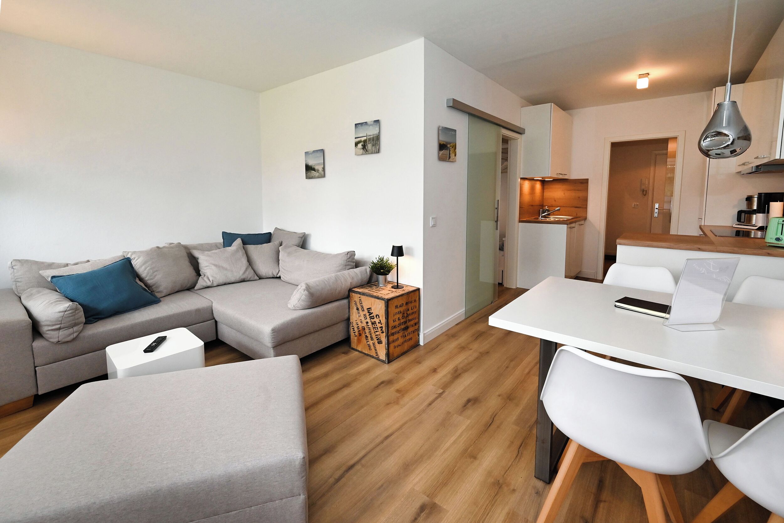 A modern living room with a sofa, a coffee table, and a dining area with a table and chairs.