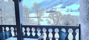 A balcony with a view of a snowy landscape and bare trees.