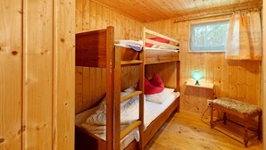 Une cabane en bois avec des lits superposés, une petite table et une fenêtre avec des rideaux.