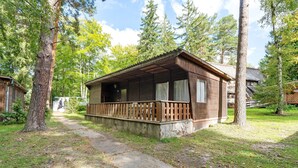 Une cabane en bois dotée d’un porche, entourée d’arbres et bordée d’un chemin en béton.