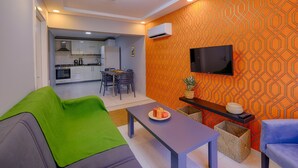 A modern living room with a sofa, a coffee table, and a TV mounted on an orange patterned wall.