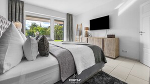 Un dormitorio moderno con una cama, un televisor y vistas al exterior.