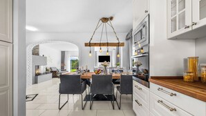 Una cocina moderna con armarios blancos, encimera de madera y una lámpara colgante.