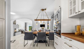 Une cuisine moderne avec des armoires blanches, un plan de travail en bois et un luminaire suspendu.