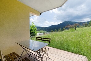 A patio with a table and chairs, overlooking a grassy field and mountains. - Holiday Home 'Les Cimes - Grand Veymont View' with Mountain View and Private Terrace (Gresse-en-Vercors)
