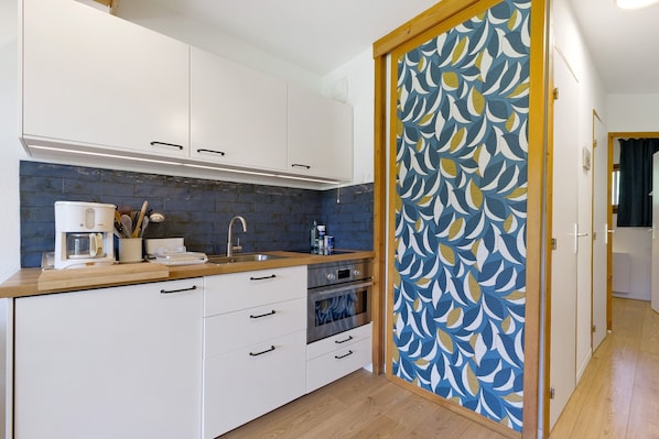 Una cucina con mobili bianchi, una parete di fondo blu e un piano di lavoro in legno.