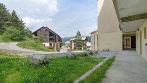 A residential area with a gravel path, houses with balconies, and a clear sky.