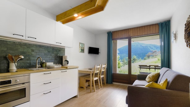 Una cucina moderna con mobili bianchi, un piano di lavoro in legno e un forno integrato.