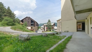 Un quartiere residenziale con un vialetto sterrato, case con balconi e cielo sereno.