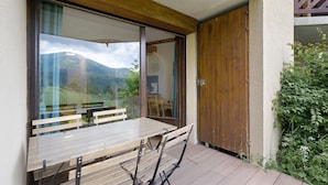 Un tavolo e sedie di legno su un balcone con vista sulle montagne.