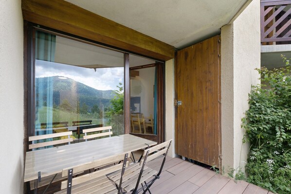 A wooden table and chairs on a balcony with a view of mountains.
